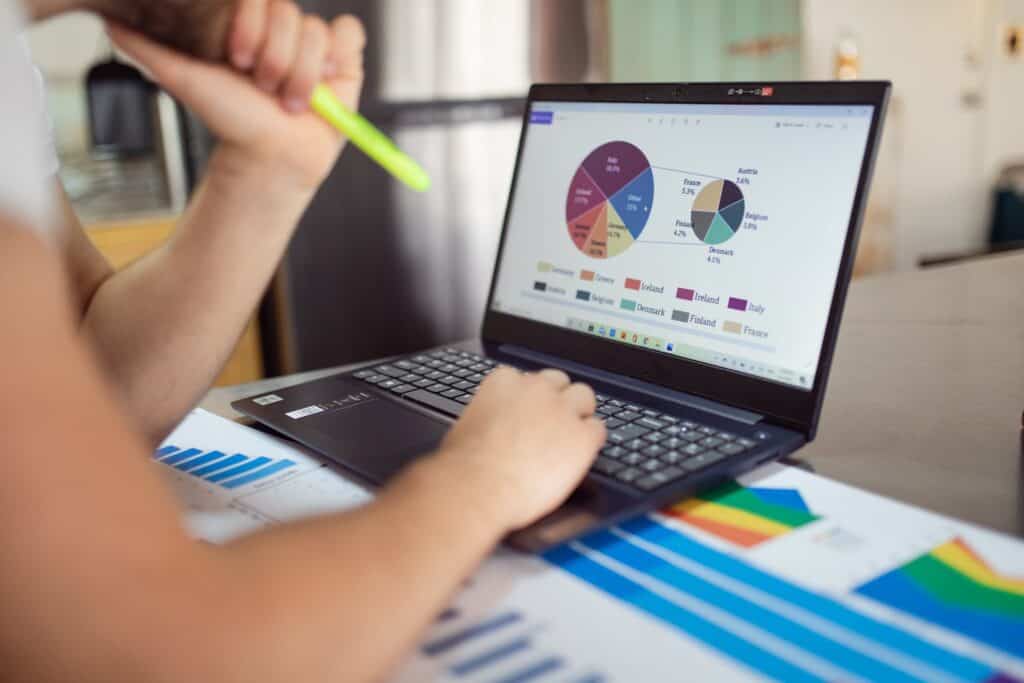 A business owner looking at a financial plan with a laptop and a pen